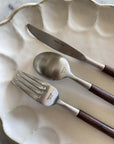 Elegant Rosewood cutlery set on white plate, featuring a knife, fork, and spoon with unique wooden handles.