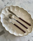 Elegant rosewood cutlery set with natural wood handles on a decorative plate, showcasing unique color and elegant design.