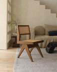 Wood-mounted dining chair with rattan weaving in a cozy living room setting, featuring teak construction and hand-crafted design.