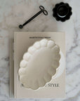 Rinka Oval Bowl 28cm made of delicate porcelain from Kaneko Kohyo, displayed on a marble surface with a book and black accessory.