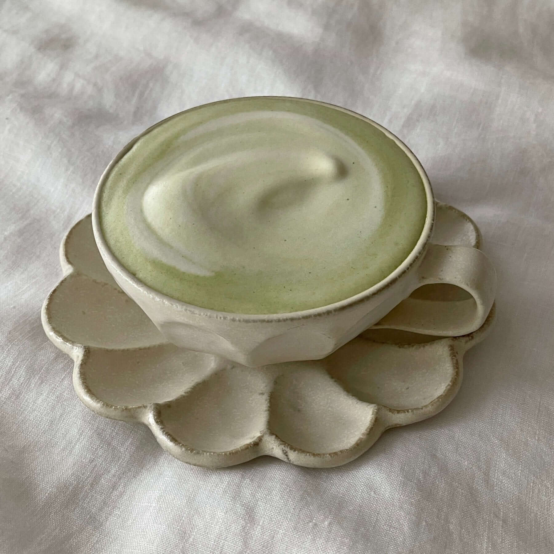 Porcelain flower-shaped soup cup set from Rinka Collection on white fabric background.