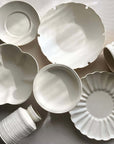 Yoshida Bundle pottery collection featuring elegant white plates, bowls, cups, saucers, and vases by Masakazu Yoshida on display.