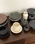 Assorted Yoshida Pottery Collection bowls and cups elegantly displayed on a wooden surface, showcasing nature-inspired patterns.