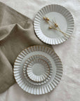 Elegant Marumitsu Barbarie plates with petal-like rim relief displayed on soft linen, perfect for enhancing any dining experience.