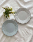 Elegant porcelain plates with lace edges and flowers display on white cloth.